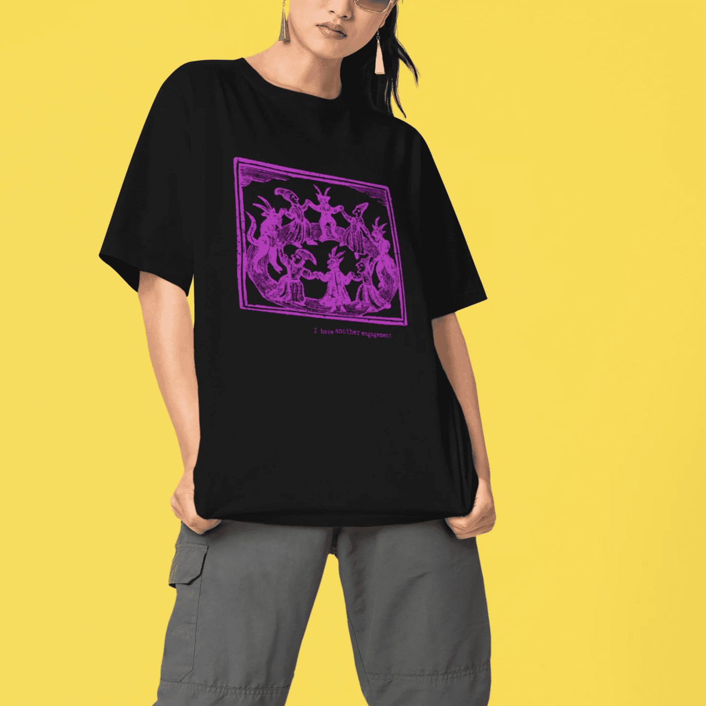 I have another engagement - woman wearing a black staple t-shirt with medieval woodcut illustration showing witches dancing i