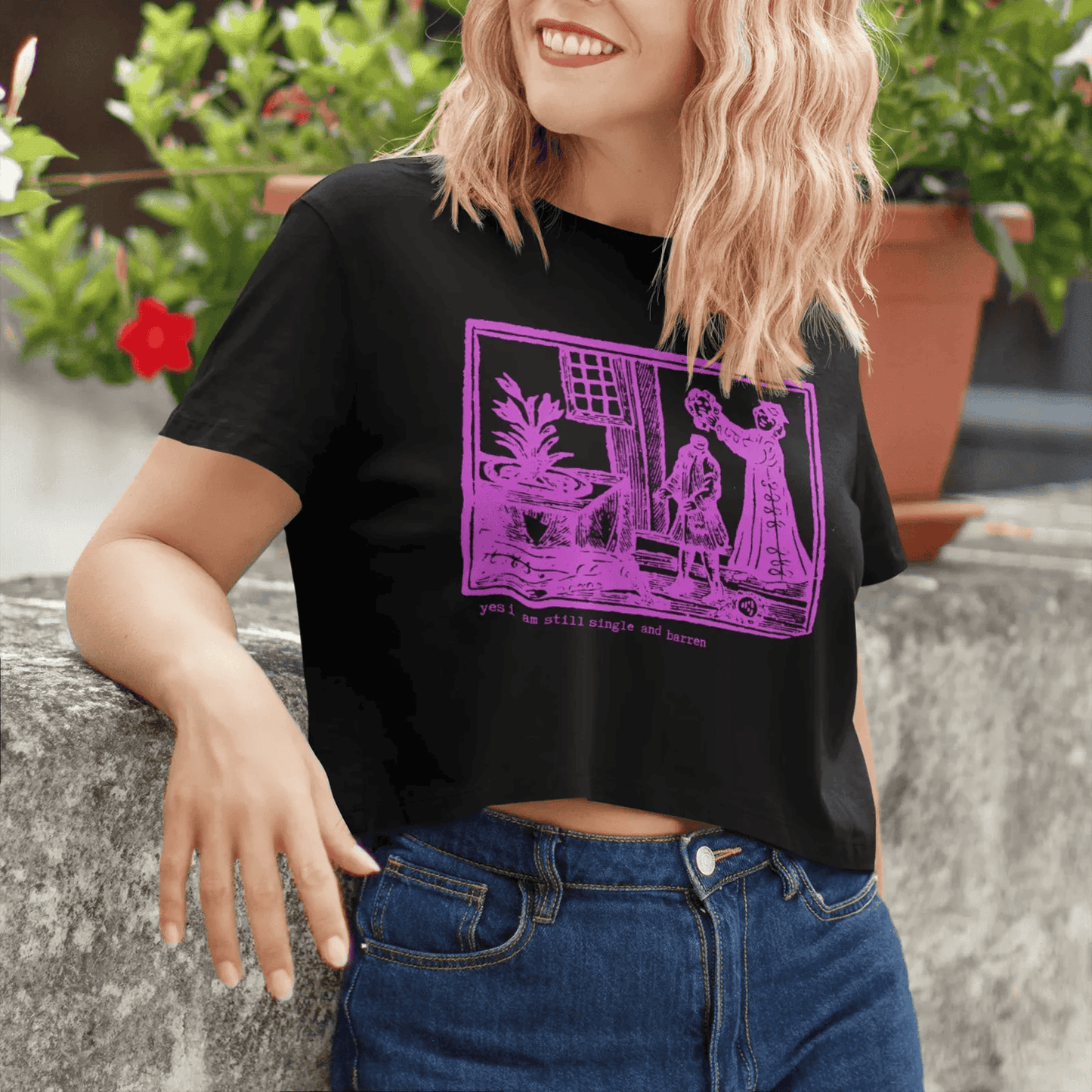 Woman wearing a black crop t-shirt with hot pink graphic saying "yes, I am still single and barren."