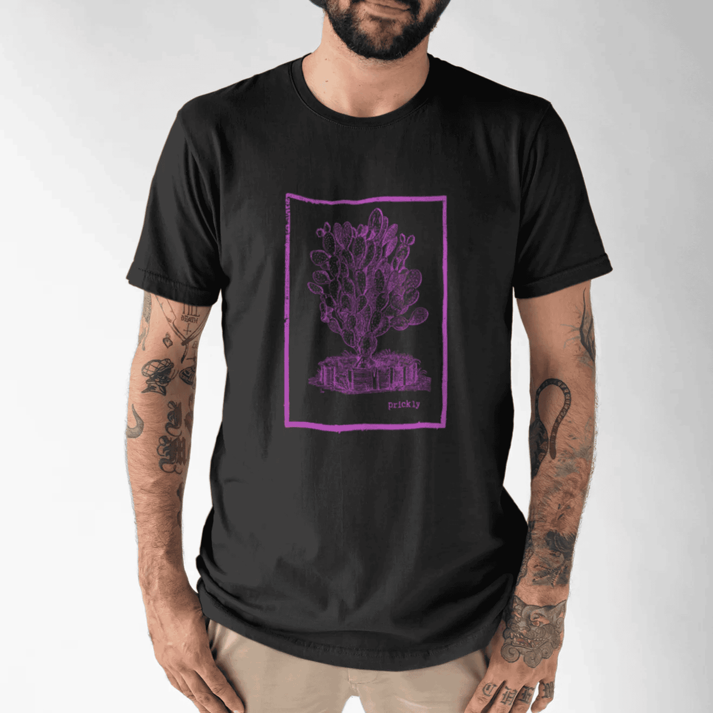 Man wearing a black t-shirt with a hot pink prickly design tee graphic design on a white background.