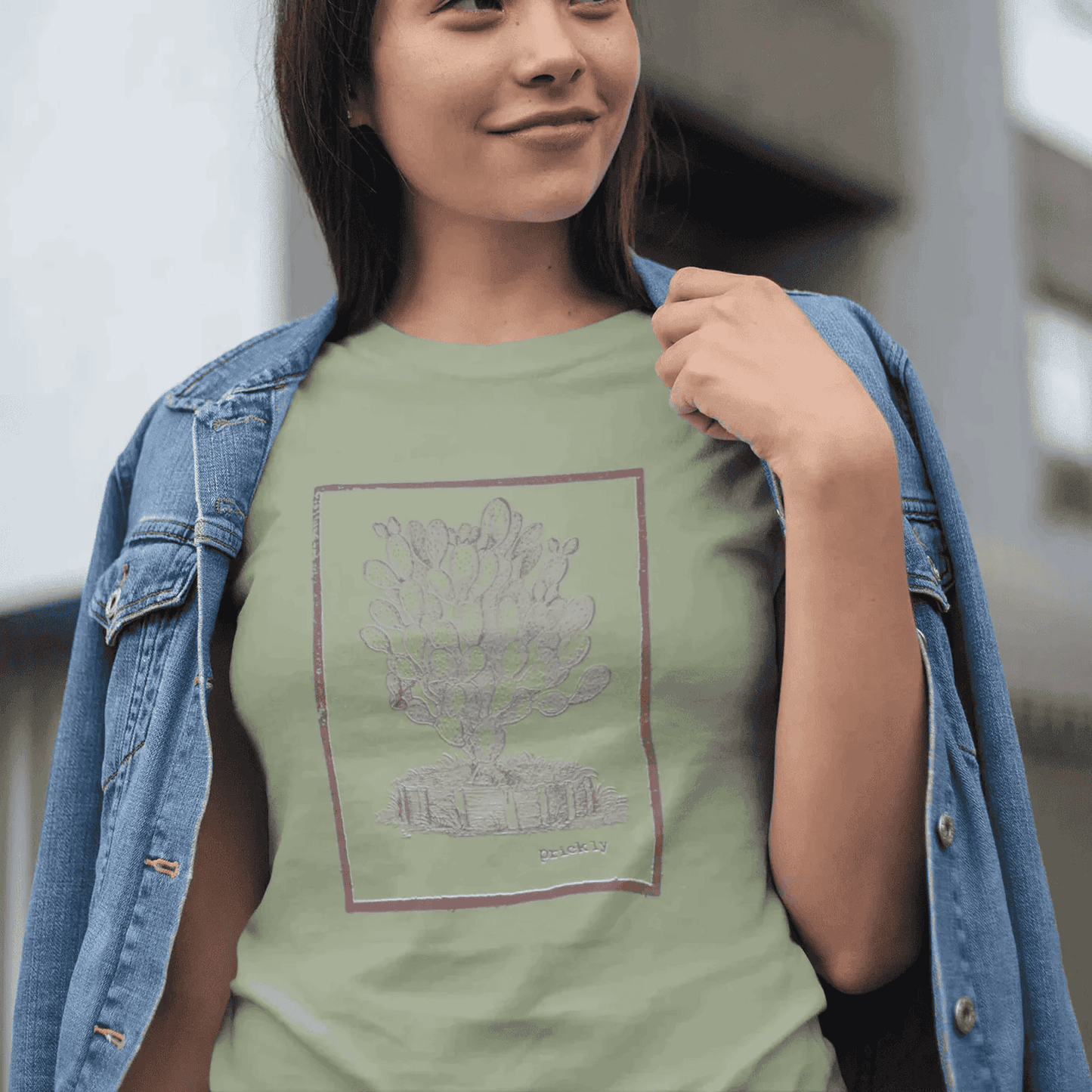 Woman wearing sage staple t-shirt with prickly design, standing outdoors